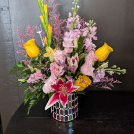 Mixed bouquet with yellow roses, pink lilies, and a mosaic vase