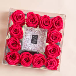 Square clear box filled with hot pink roses around a crystal center