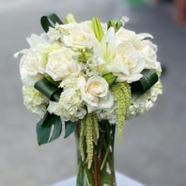 White roses and lilies arranged in a clear glass vase