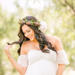 Pregnant woman in a white dress wearing a floral crown