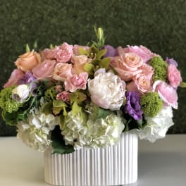 Pink and peach roses with white hydrangeas in a ribbed white vase