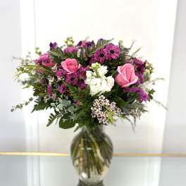 Pink roses and purple daisies in a glass vase