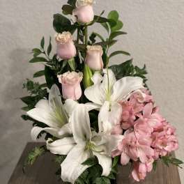 Pink roses and white lilies arranged in a black vase with pink alstroemeria