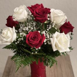 Red and white roses in a red vase with baby's breath