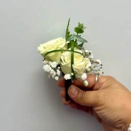 Small white rose boutonniere with baby's breath and greenery