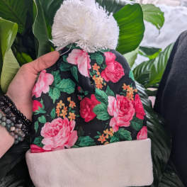 Floral knit beanie with pink roses and a white pom-pom