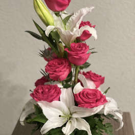 Pink roses and white lilies arranged in a black vase