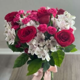 Bouquet of pink roses and white alstroemeria in a glass vase