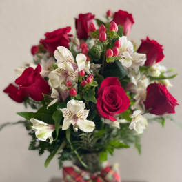 Bouquet of red roses and white alstroemeria in a glass vase with plaid ribbon