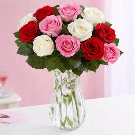 Bouquet of red, pink, and white roses in a clear glass vase