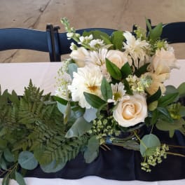 White floral arrangement with roses and daisies in a dark vase