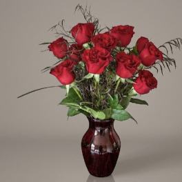 Red roses arranged in a burgundy glass vase