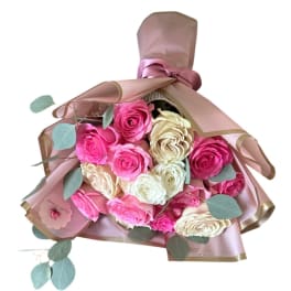 Bouquet of pink and cream roses wrapped in blush paper with ribbon