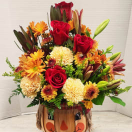 Autumn bouquet of red roses and orange chrysanthemums in a pumpkin container