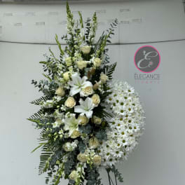 Tall white floral standing spray with lilies, roses, and daisies