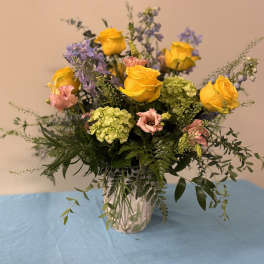 Yellow roses and pink blooms in a glass vase