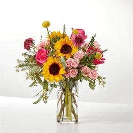 Bouquet of sunflowers and pink roses in a clear glass vase