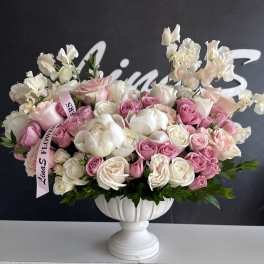Pink and white rose arrangement in a white pedestal vase