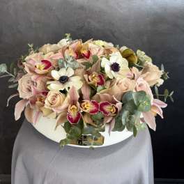Blush roses and orchids arranged in a white hat box
