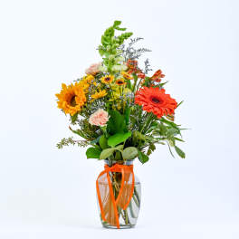 Mixed bouquet in a glass vase with an orange ribbon