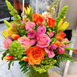 Bright mixed bouquet of pink, orange, and green flowers in a clear glass vase