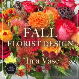 Colorful fall flower arrangement with orange dahlias, red and orange roses, and rust chrysanthemums.