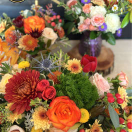 Colorful mixed flower arrangements with orange roses, chrysanthemums, and purple asters in vases