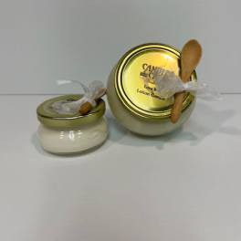 Two small candle jars with gold lids and wooden spoons tied on top