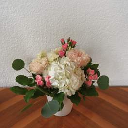 Pink roses and white hydrangeas arranged in a white vase