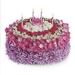 Round pink and purple floral cake with lit candles
