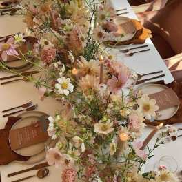 Pastel floral centerpiece running down a set table with candles and place settings
