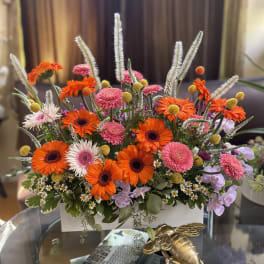 Bright mixed flower arrangement in a white rectangular container