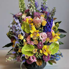 Colorful mixed bouquet in a black vase with tall purple and green spikes