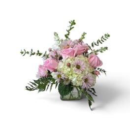 Pink roses and pale daisies arranged in a square glass vase