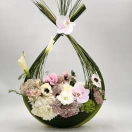 Floral arrangement in a curved green frame with pink and white blooms