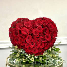 Heart-shaped arrangement of red roses with white filler flowers