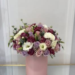 Mixed pink, lavender, and white roses arranged in a pink box