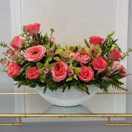 Pink roses and orchids arranged in a white bowl vase
