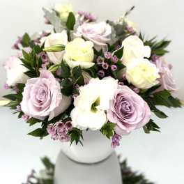 Pastel roses and white blooms arranged in a white vase