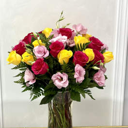 Bouquet of pink and yellow roses in a clear glass vase