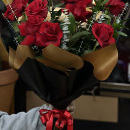 Bouquet of red roses wrapped in black and gold paper with a red ribbon