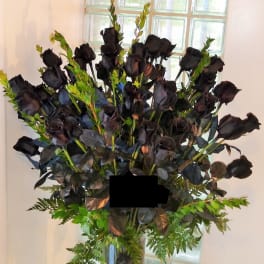 Tall bouquet of black roses in a glass vase