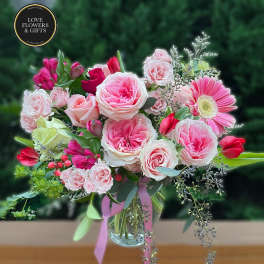 Pink and white rose bouquet with tulips and a gerbera daisy in a clear glass vase