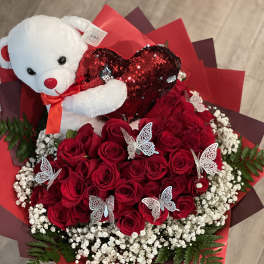 Red rose bouquet with a teddy bear holding a heart and butterfly picks