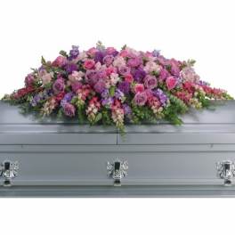 Large pink and purple casket spray of roses and mixed flowers on a silver casket