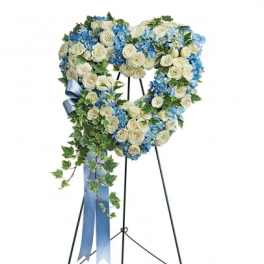 Heart-shaped floral wreath on a stand with blue and white flowers