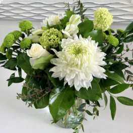 White and green floral arrangement in a glass vase