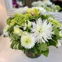 White and green floral bouquet in a glass vase
