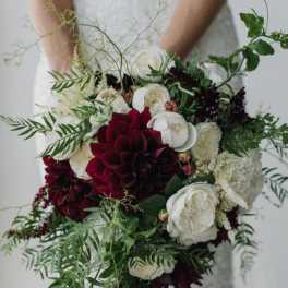 Bride holding a cascading bouquet of white and deep red flowers