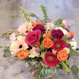 Mixed bouquet of roses, gerbera daisies, and carnations in a glass vase